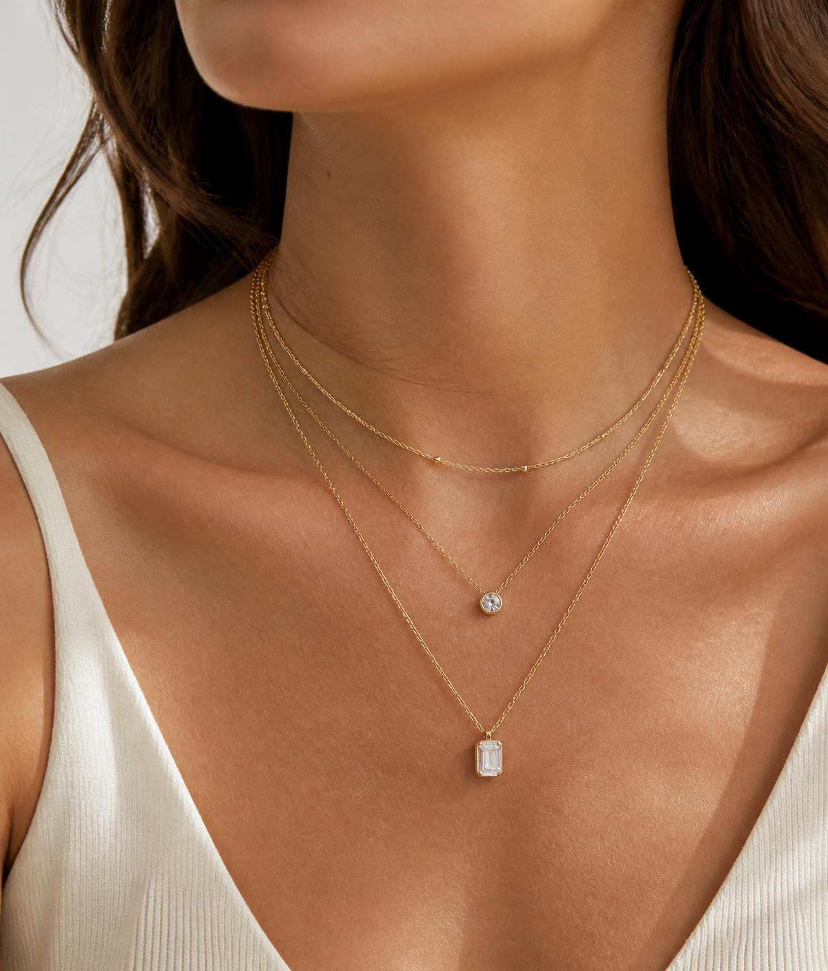 Model wearing layered gold Upretino necklaces